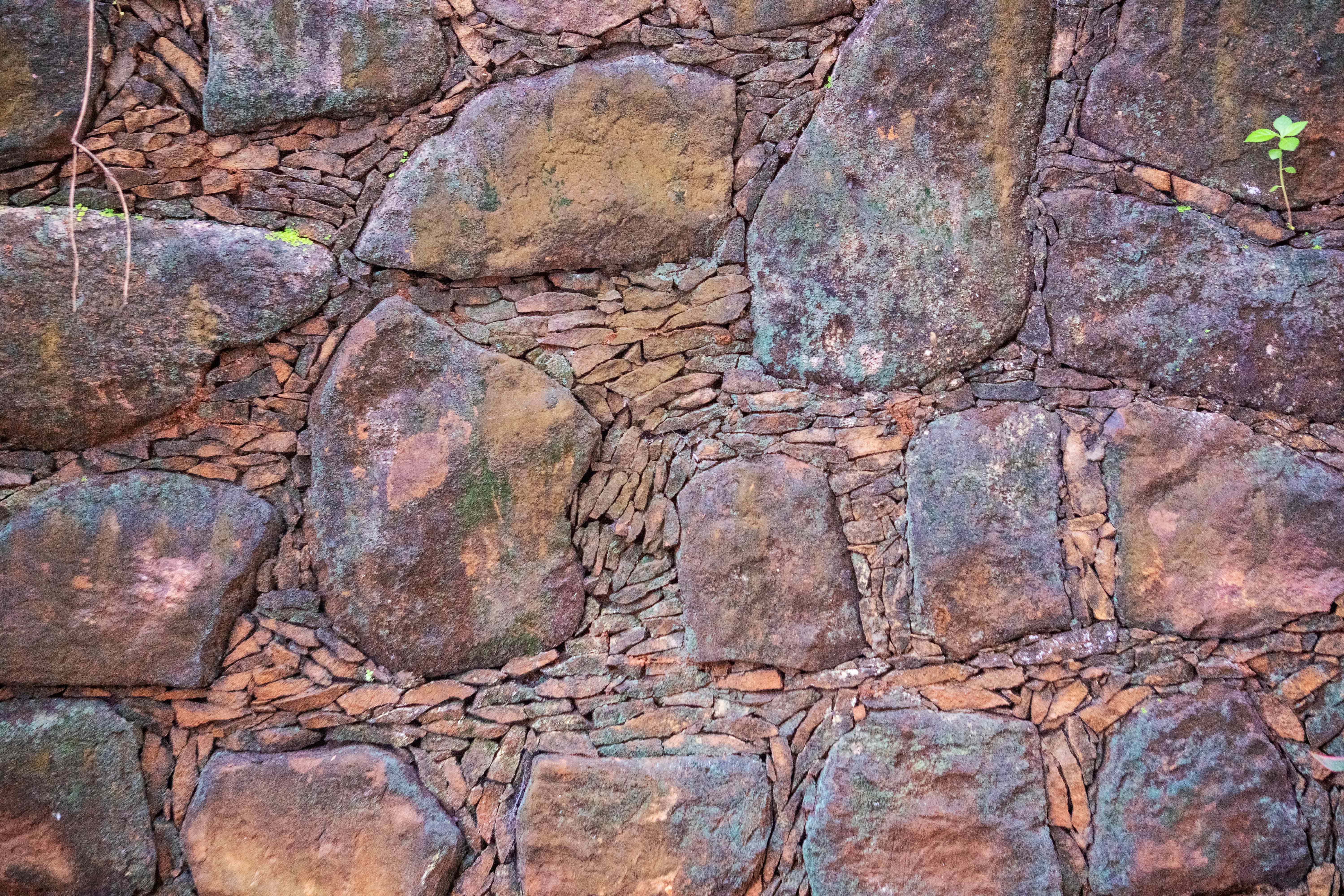 Weathered Granite Fieldstone Wall Texture with Mossy Natural Rock Surface and Rustic Masonry Detail